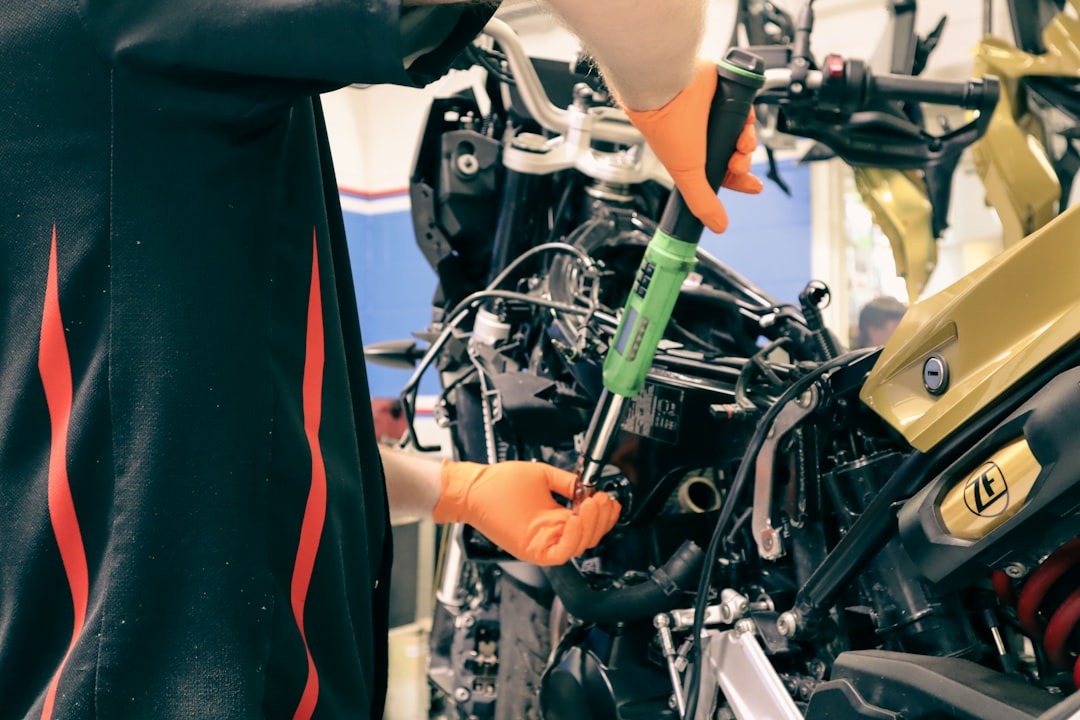 Mechanic tightens motorcycle engine component with torque wrench.